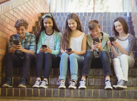 Kinderen zitten op een trap met hun smartphone in hun handen