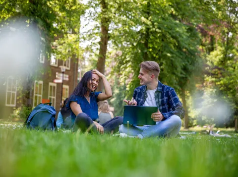 Studenten zitten te kletsen buiten op de campus
