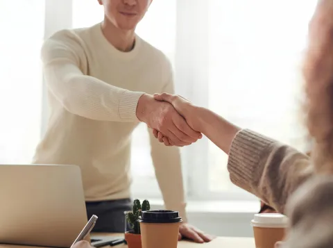 Twee mensen schudden handen tijdens een sollicitatiegesprek