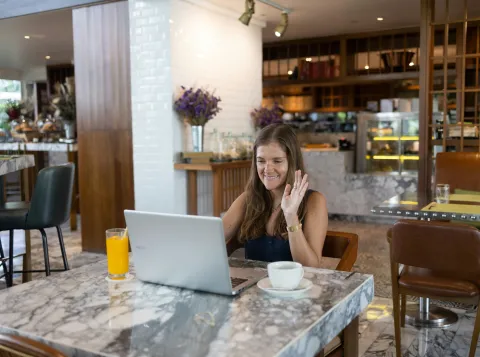 Woman sits at a table behind her laptop.
