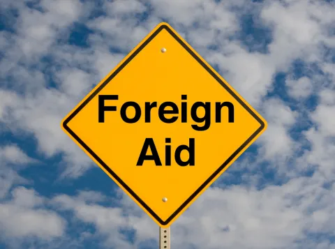 Yellow sign with black letters that says 'Foreign aid'. 