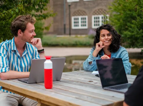Two employees sitting outside with laptops