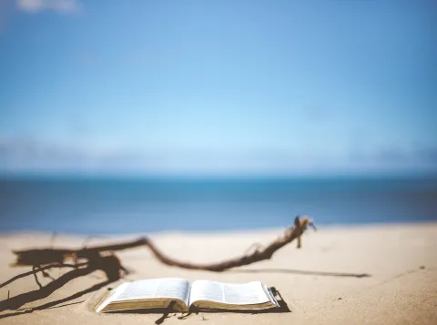Een opengeslagen boek op een zandstrand