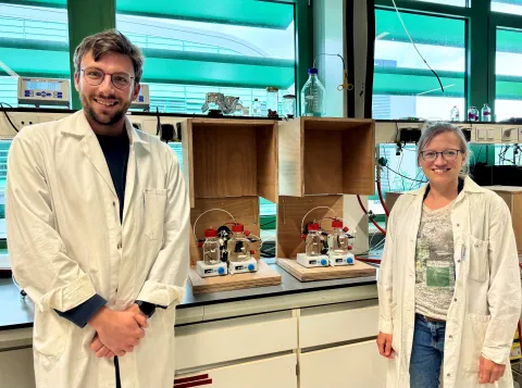 Dr Conall Holohan (left) and dr Cornelia Welte in white lab coats next to their bioelectrochemical systems in the lab