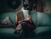 Person is laying on the sofa and reading a boko