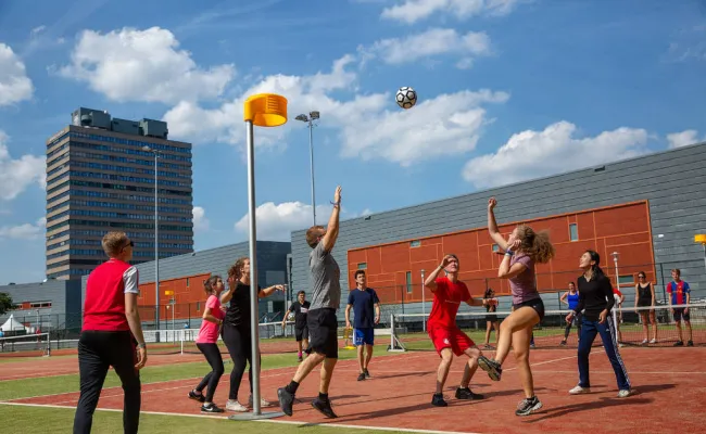 Groep studenten die buiten korfbal speelt op de velden van het sportcentrum