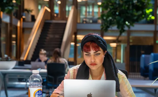 Een student is aan het werk op haar laptop op de campus van de Radboud Universiteit.