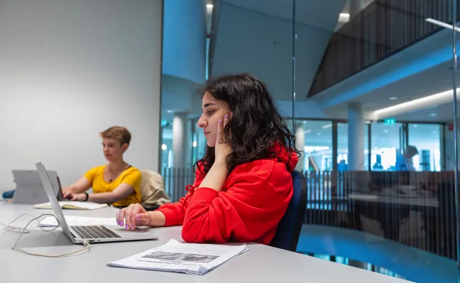 Een student is aan het werk op z'n laptop op de campus van de Radboud Universiteit.