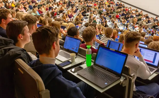 Studenten in een collegezaal met laptops open