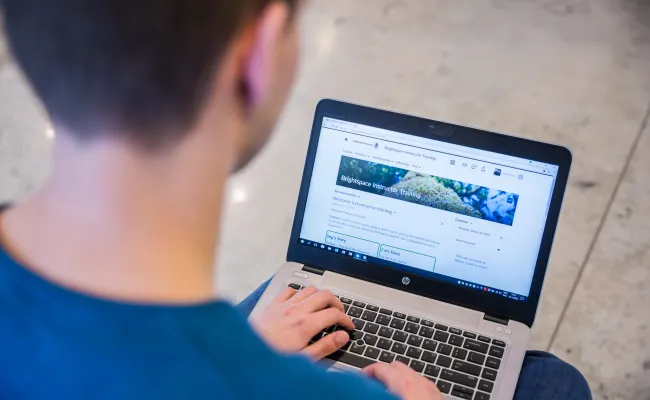Jongen die Brightspace startpagina bekijkt op laptop