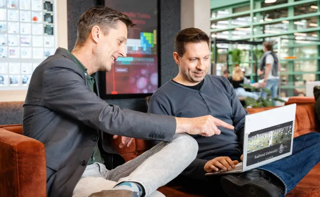 Twee mannen bespreken iets met hun laptop