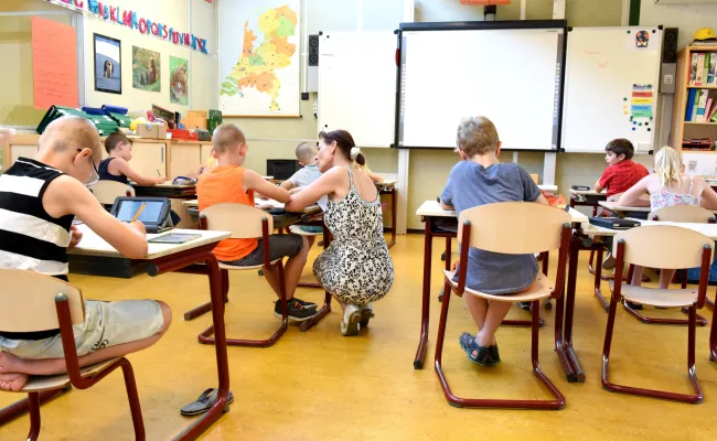 Kinderen in een klaslokaal onder begeleiding van een leraar