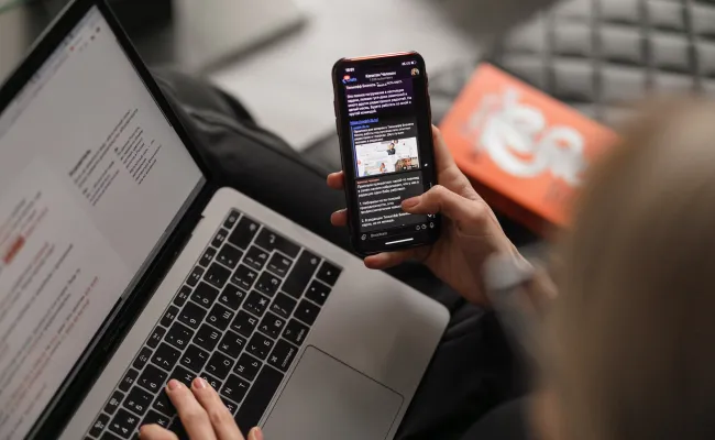 A person looking at their phone and laptop.