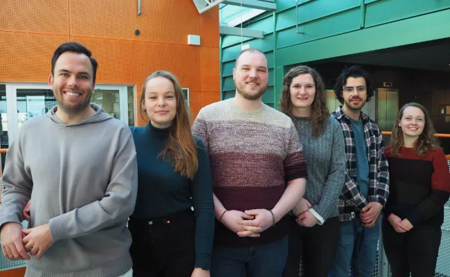 Photo of the members of the RIBES PhD council, smiling and standing next to each other in a hallway