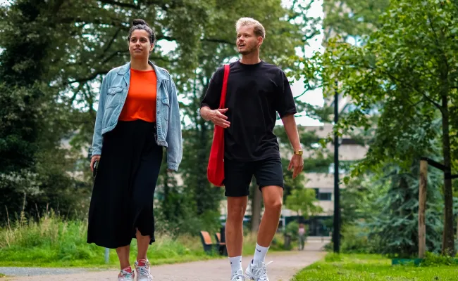 Twee collega's wandelen in het bos bij het Erasmusgebouw