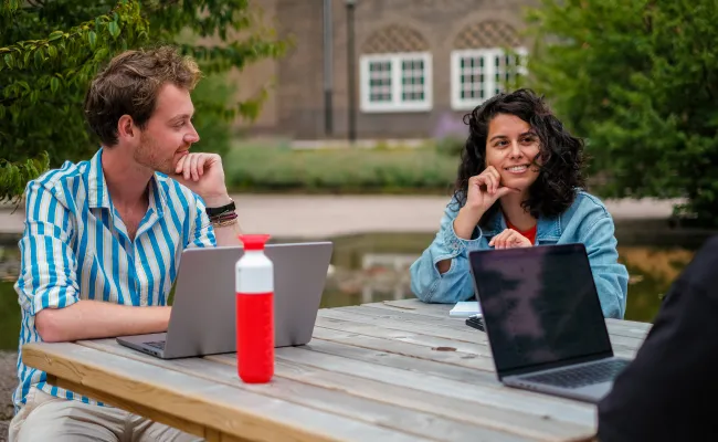 Two employees sitting outside with laptops