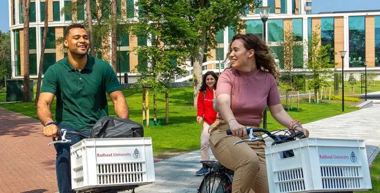 Twee studenten fietsen over de campus van de Radboud Universiteit