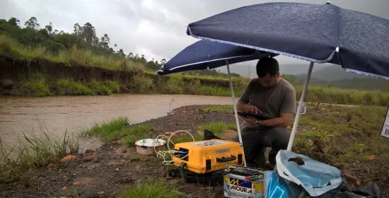 Foto van een watergebied in Brazilie met een onderzoeker die metingen uitvoert ernaast