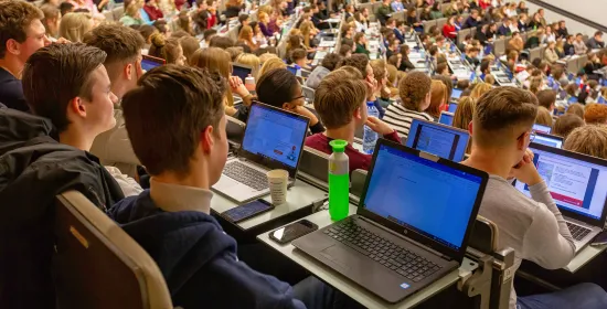 Studenten in een collegezaal met laptops open