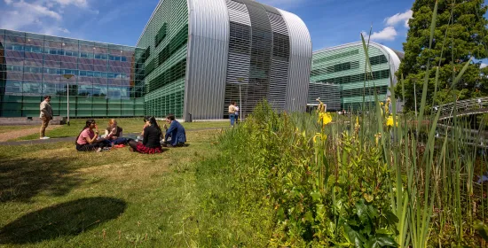 Studenten buiten in het gras achter het Huygensgebouw