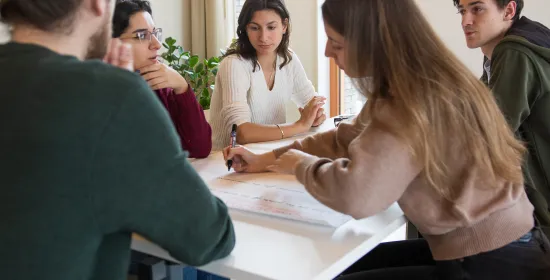 Kleine groep studenten die aan tafel zitten