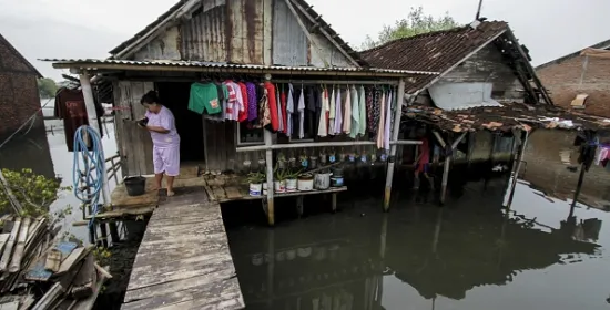 Woman tends to washing hanging on the porch of her wooden shack on stilts in Indonesia