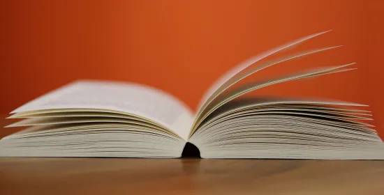 Een opengeslagen boek en een oranje muur