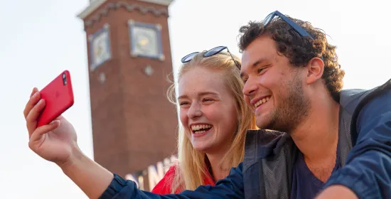 Studenten die een foto nemen voor het centraal station in Nijmegen