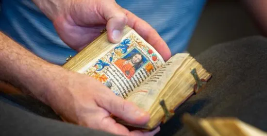 Een persoon houdt een historisch boek in zijn handen