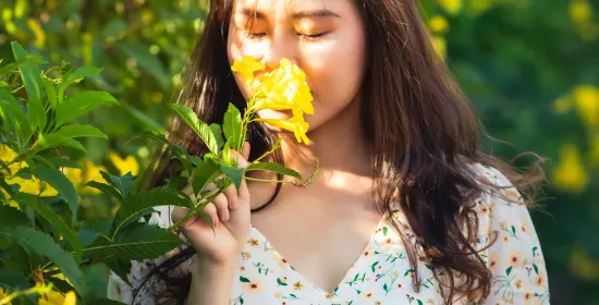 A woman smelling a yellow rose