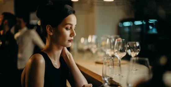 Alleenstaande vrouw aan de bar met haar mobiel in de hand