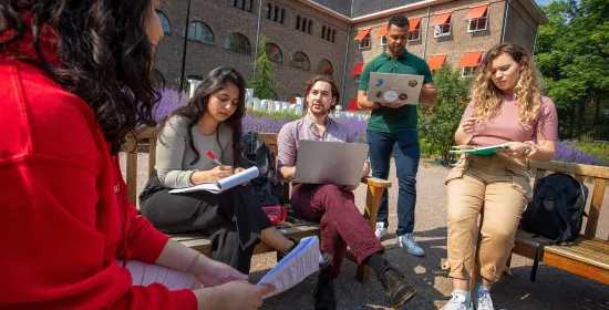 Groep studenten aan het werk buiten op de campus