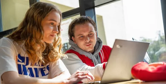 Studenten samen aan het werk op een laptop.