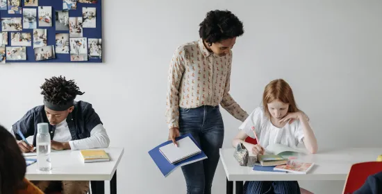 Vrouwelijke docent helpt leerling in de klas