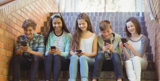 Kinderen zitten op een trap met hun smartphone in hun handen