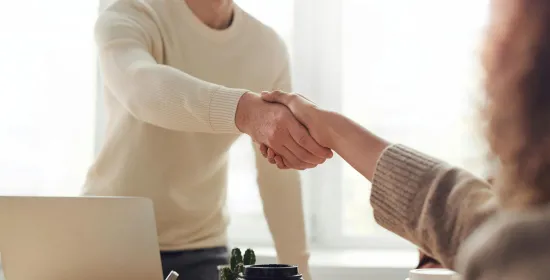Twee mensen schudden handen tijdens een sollicitatiegesprek