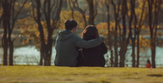 Man en vrouw zitten met arm over elkaars schouders
