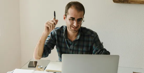 Man aan een bureau aan het werk op laptop