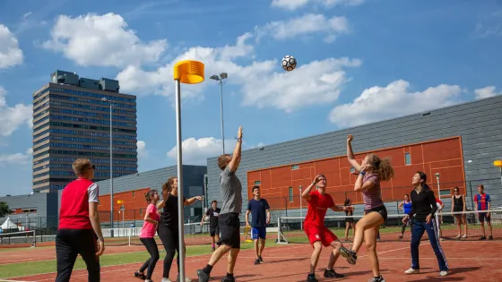 Groep studenten die buiten korfbal speelt op de velden van het sportcentrum