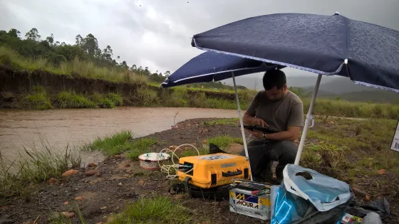 Foto van een watergebied in Brazilie met een onderzoeker die metingen uitvoert ernaast