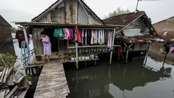 Woman tends to washing hanging on the porch of her wooden shack on stilts in Indonesia