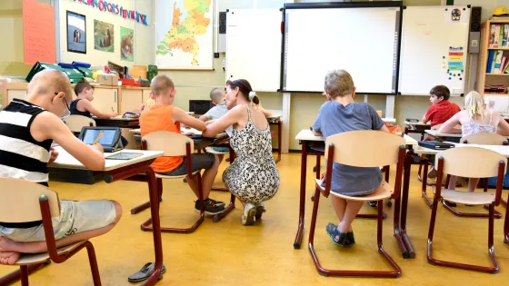 Kinderen in een klaslokaal onder begeleiding van een leraar