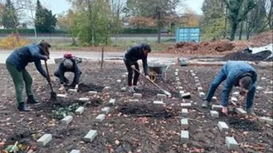 Medewerkers en studenten graven in een moestuin