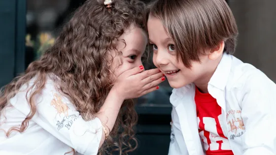 Two children gossiping to each other