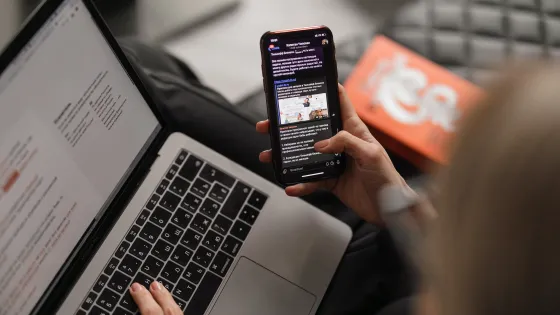 A person looking at their phone and laptop.