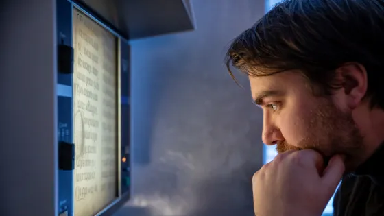Onderzoeker bekijkt oude teksten via microfilmlezer