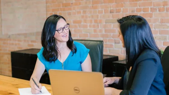 Twee vrouwen praten met elkaar aan een bureau