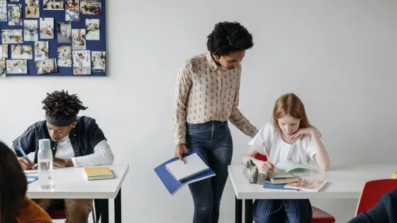 Vrouwelijke docent helpt leerling in de klas