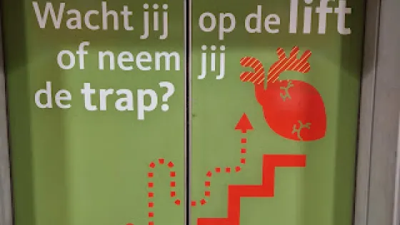 Liftdeur met opschrift 'Wacht jij op de lift of neem jij de trap?'
