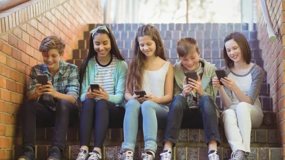 Kinderen zitten op een trap met hun smartphone in hun handen